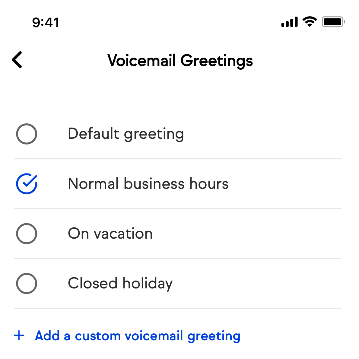 Voicemail greetings screen in the Keap mobile app showing a list of saved voicemail greetings. Each greeting displays its name and a checkbox on the right side. One greeting has its checkbox checked, indicating it is the active greeting. An Add a custom voicemail greeting button is visible at the bottom of the list.